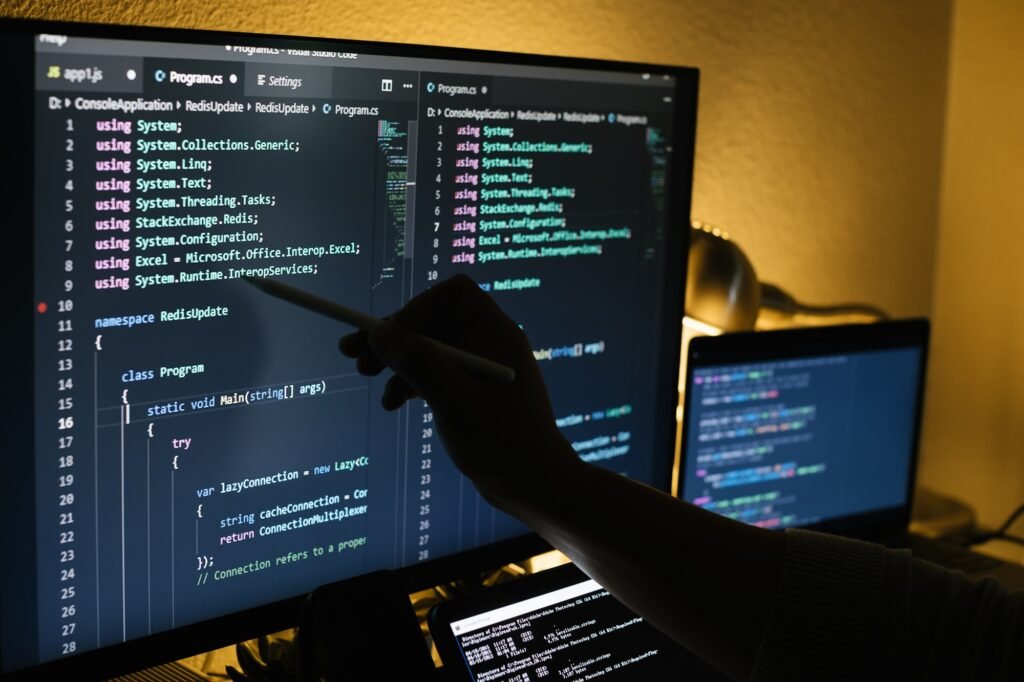Man working at night coding and pointing on a screen with a pen